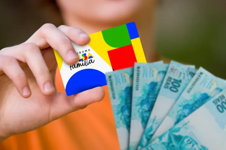 Cartão do programa Bolsa Família sendo segurado por uma pessoa ao lado de notas de dinheiro, representando a antecipação do benefício em cidades brasileiras.