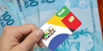 Cartão do programa Bolsa Família sobre notas de 100 reais, destacando a possibilidade de pagamento antecipado em março para moradores de MG, RJ e SP.