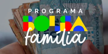Mãos segurando cédulas de reais com logotipo do Programa Bolsa Família