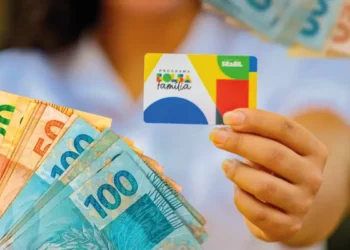 Cartão do Bolsa Família em primeiro plano, com notas de 50, 100 e 200 reais ao fundo, simbolizando a diminuição no número de beneficiários do programa em março de 2026