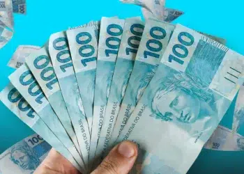 Mão segurando leque de cédulas de R$ 100 reais
