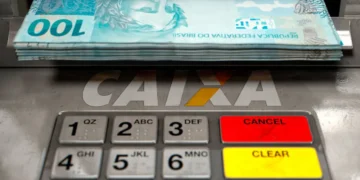 Caixa eletrônico da Caixa Econômica Federal dispensando cédulas de R$ 100, representando a liberação do Saque Calamidade do FGTS de até R$ 6.220 para trabalhadores de municípios contemplados