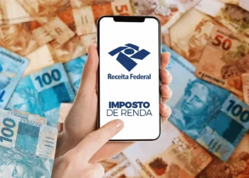 Celular mostrando aplicativo da Receita Federal para consulta do lote residual do Imposto de Renda 2026 com notas de real ao fundo