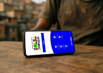 Pessoa segurando celular com o aplicativo do Programa Bolsa Família aberto na tela, mostrando as opções de consulta e calendário de pagamentos