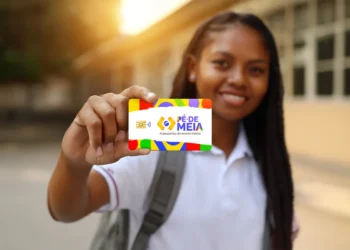 Jovem estudante sorrindo e exibindo o cartão do Pé-de-Meia, programa que pode liberar parcelas de R$ 200 e R$ 1.000 de 2025 nas próximas janelas de pagamento