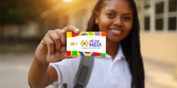 Jovem estudante sorrindo e exibindo o cartão do Pé-de-Meia, programa que pode liberar parcelas de R$ 200 e R$ 1.000 de 2025 nas próximas janelas de pagamento