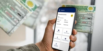 Pessoa segura celular exibindo tela de CNH digital ao lado de carteira física de motorista