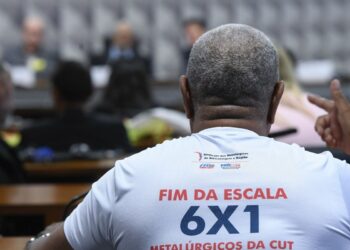 Trabalhador participa de audiência na Câmara usando camiseta com a frase “Fim da escala 6x1”, tema debatido na CCJ sobre jornada de trabalho.