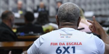 Trabalhador participa de audiência na Câmara usando camiseta com a frase “Fim da escala 6x1”, tema debatido na CCJ sobre jornada de trabalho.