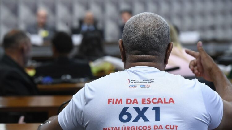 Trabalhador participa de audiência na Câmara usando camiseta com a frase “Fim da escala 6x1”, tema debatido na CCJ sobre jornada de trabalho.