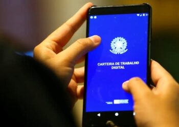 Mãos segurando um smartphone com o aplicativo da Carteira de Trabalho Digital aberto, ilustrando o debate sobre a redução da jornada de trabalho.