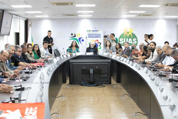 Autoridades e técnicos reunidos em mesa oval discutindo políticas sociais na Sede do Governo Federal