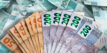 Notas de real brasileiro de R$50 e R$200 seguradas na mão, representando o tema do Imposto de Renda e prazos da declaração 2026.