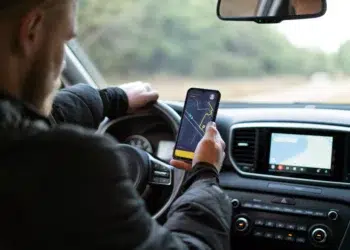 Motorista segura celular com app de navegação enquanto dirige carro moderno