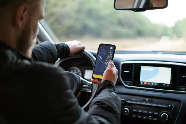 Motorista de aplicativo está obrigado a entregar declaração de Imposto de Renda em 2026? Descubra! 1 Motorista segura celular com app de navegação enquanto dirige carro moderno