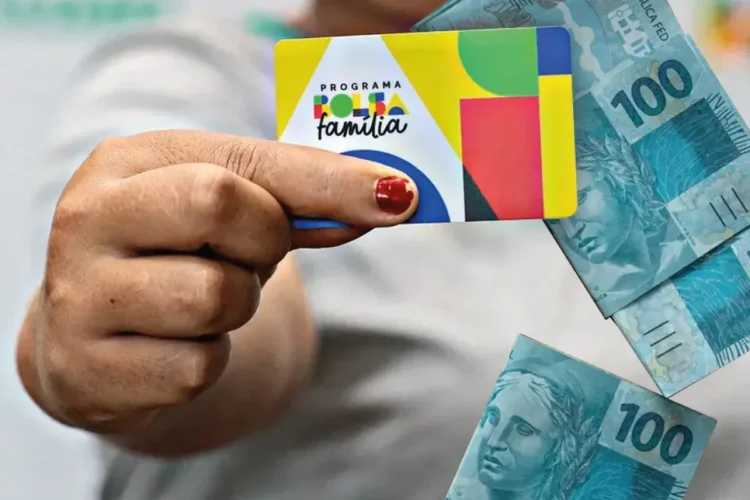 Bolsa Família: pagamento antecipado em março atinge 171 cidades 1 Uma pessoa segurando um cartão do Bolsa Família junto a cédulas de R$ 100, ilustrando o pagamento antecipado do benefício.