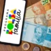 Celular com logo do Programa Bolsa Família apoiado sobre notas de R$ 20, R$ 50 e R$ 100, representando o pagamento do benefício em março de 2026