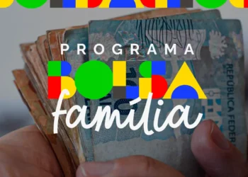 Mão segurando notas de reais com logo colorida do Bolsa Família sobreposta