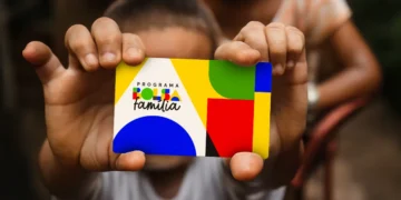 Criança segurando cartão colorido do Programa Bolsa Família com fundo desfocado