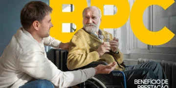 Homem idoso sentado em cadeira de rodas segura copo de água enquanto conversa com cuidador