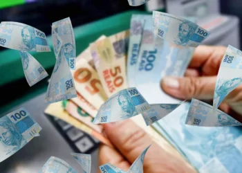 Pessoa segurando cédulas de dinheiro brasileiro representando pagamento liberado pelo INSS para beneficiários no Brasil