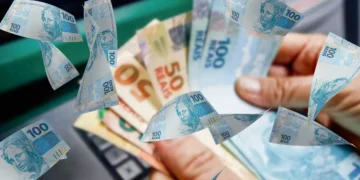Pessoa segurando cédulas de dinheiro brasileiro representando pagamento liberado pelo INSS para beneficiários no Brasil