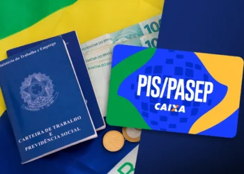 Carteira de trabalho, cartão PIS/Pasep, cédulas e moedas sobre bandeira do Brasil