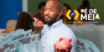 Homem segurando dinheiro e um cofrinho no ambiente de sala de aula, representando o saque de R$ 2.000 do Pé-de-Meia e o bônus de R$ 200 para estudantes.