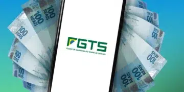 Governo anuncia estudo para liberar R$ 17 bilhões do FGTS a trabalhadores endividados 4 Smartphone exibe logo do FGTS cercado por notas de R$ 100 sobre fundo azul e verde gradiente.