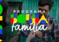 Pai segura criança no colo com logotipo colorido do Programa Bolsa Família sobreposto à imagem.